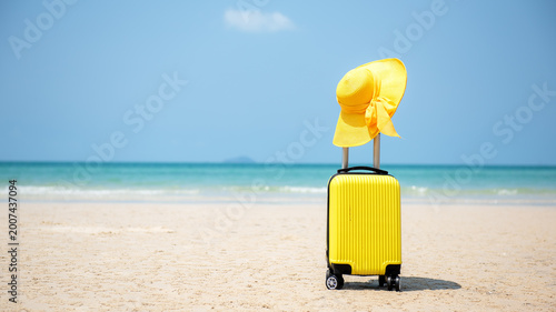 Summer travel and planing with yellow suitcase luggage in the sand beach. Travel in the holiday trips, airplane and blue sky background. Summer and Travel Concept