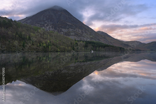 Canvas-taulu Reflections of mountains at sunrise with peaceful boathouse on shoreline, Crummock Water, Lake District, UK