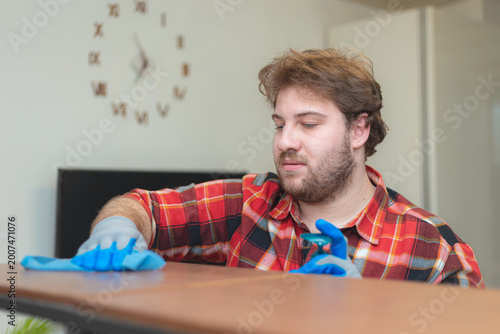 Fotografia A bearded young Caucasian man washes a shelving unit in a room.