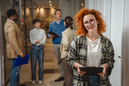 Fényképezés Redhead woman holding clipboard smiling in office hallway
