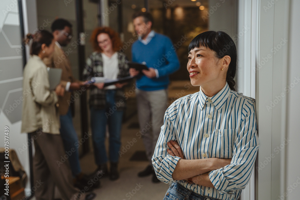 Obraz premium Confident asian businesswoman smiling while leaning in modern office space
