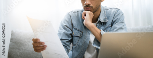 Fotografie Household financial economic concept, Stressed Young Asian adults are looking at credit card bills issued documents, and apartment loan mortgages and worrying about having no money to pay