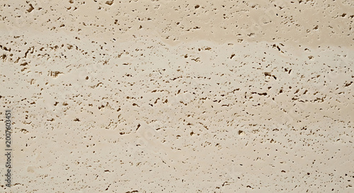 Detailed macro photography of natural beige travertine stone texture showcasing organic porous holes and limestone surface for architectural and design projects