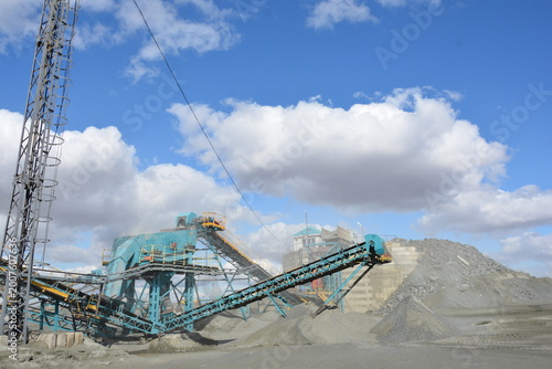 industrial stone crushing plant and conveyor system at gravel quarry for mining under blue sky