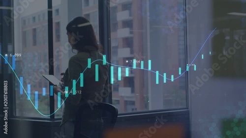 Woman tapping tablet by corner window and animating candlestick overlay while analyzing market data