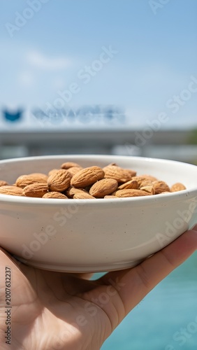 Healthy Snack of Raw Almonds in a White Bowl Held by Hand at a Tropical Resort Pool