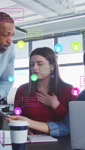 Vertical video: Mentor pointing at phone sparking chat overlays while woman taking notes in office