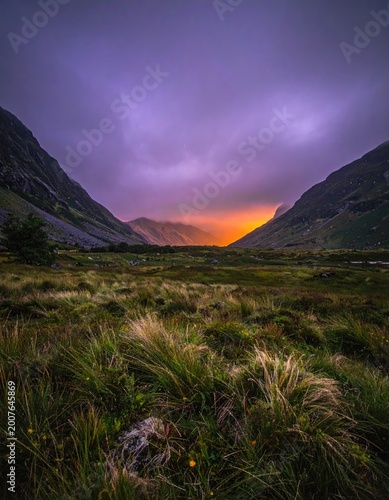 Vivid sunset casts glow over mountain valley scene