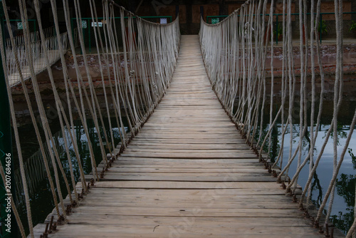 A suspension rope bridge over calm water.