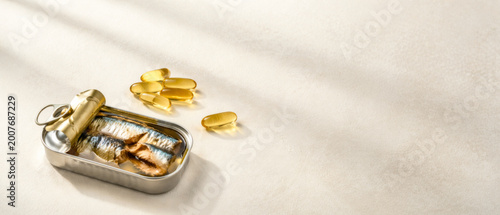 Canned sardines and omega capsules on neutral background