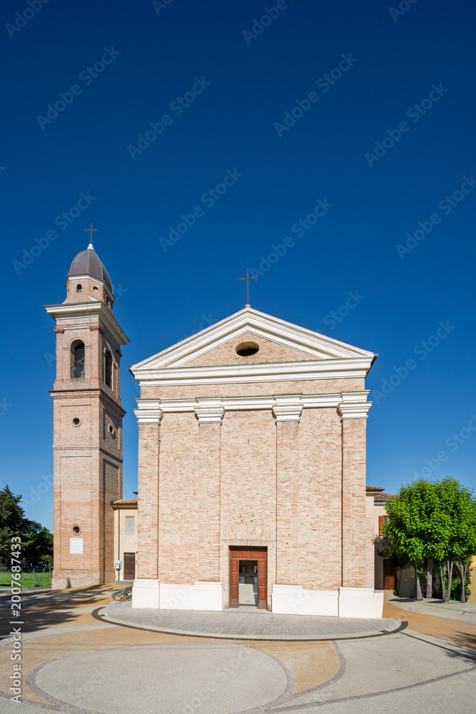 Fototapeta premium Front view of the Church of San Rocco in Trebbio near Montegridolfo in the Emilia Romagna region of Italy showing brick facade and bell tower under clear blue sky in morning light