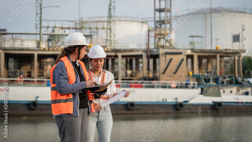 Photos Two engineers stand by water, reviewing plans
