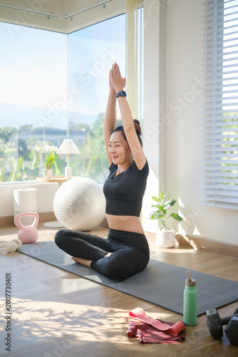 Fit woman doing a seated yoga stretch indoors, enjoying a calm and mindful moment with natural sunlight and minimal decor.