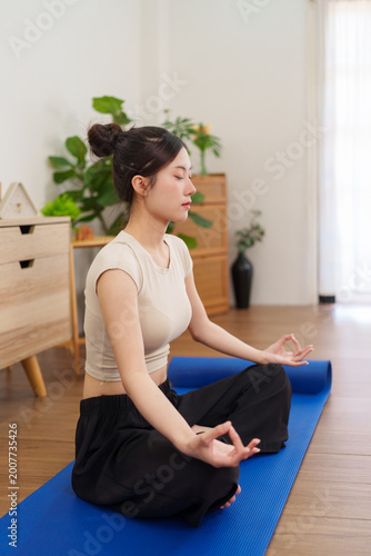 Obraz na plátne young Asian women practicing yoga meditation lotus pose on blue mat at home livi