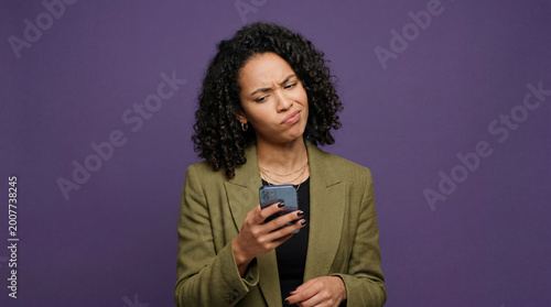Young woman showing confused reaction while looking at mobile phone