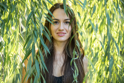 Portrait of a young beautiful woman posing in willow foliage