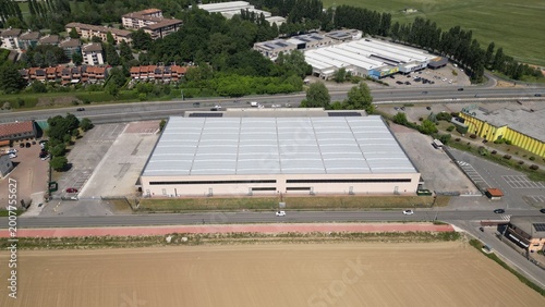Fotografía Aerial View of a Large Industrial Warehouse: An expansive industrial complex with a vast warehouse structure featuring a modern, grid-like roof is seen from above