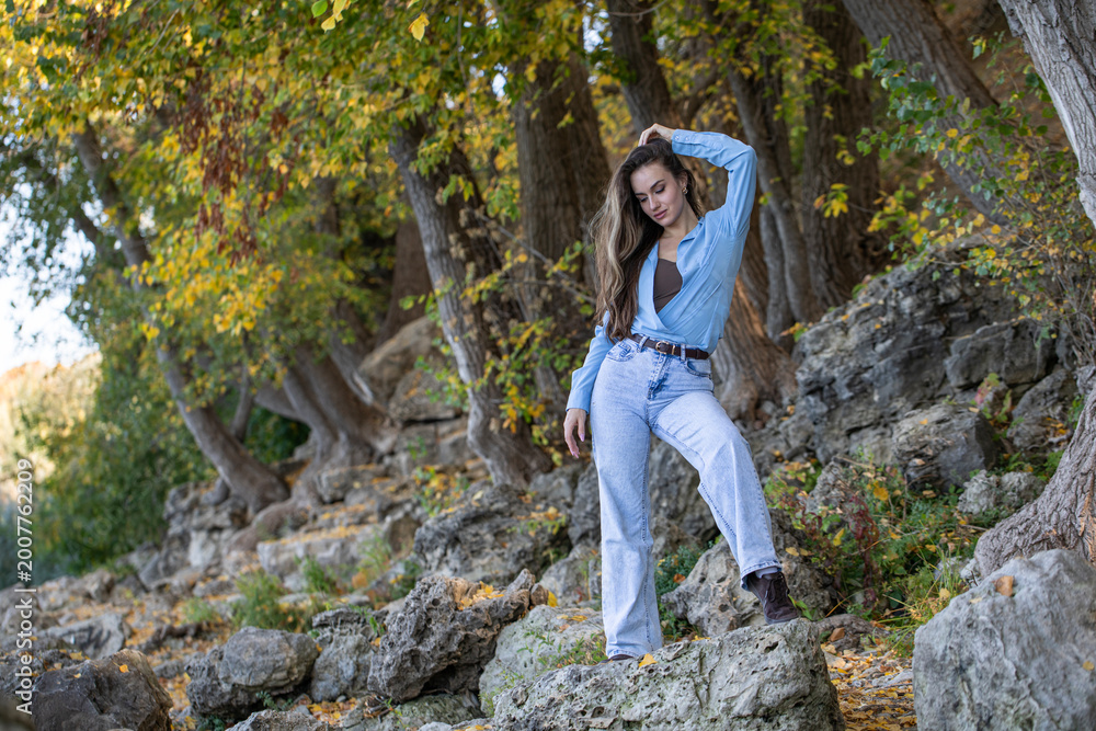 Naklejka premium Full body portrait of a young beautiful woman in blue jeans