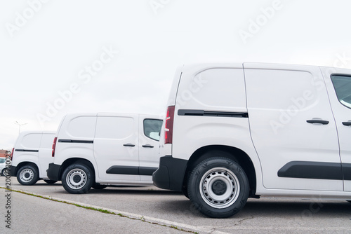 Billede på lærred White delivery vans are parked in rows