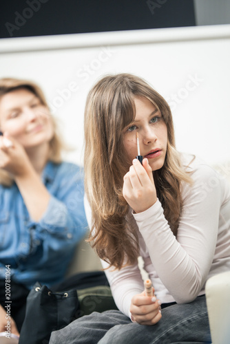 Cuadro en lienzo Young woman applying makeup concealer to her face