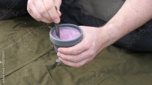 Camper stirring a hot drink in outdoor cup