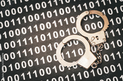 Cyber crime and digital law enforcement concept with handcuffs on binary code