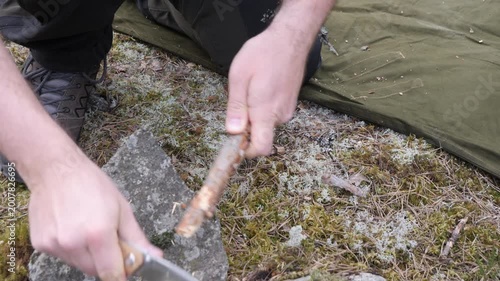 Camper Preparing Wood Shavings for Fire in Wilderness