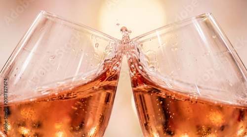 Close up rose wine glasses toasting bubbly drink.