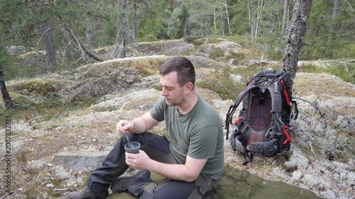 Hiker Resting with Cup in Rocky Forest Wilderness