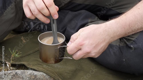 Camper Stirring Hot Drink in Metal Mug Outdoors