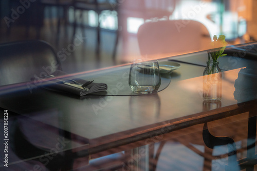 Elegant Restaurant Table Setting Seen Through Window Reflections, Empty Cafe Interior with Glass, Flower Vase, Soft Light and Moody Bokeh
