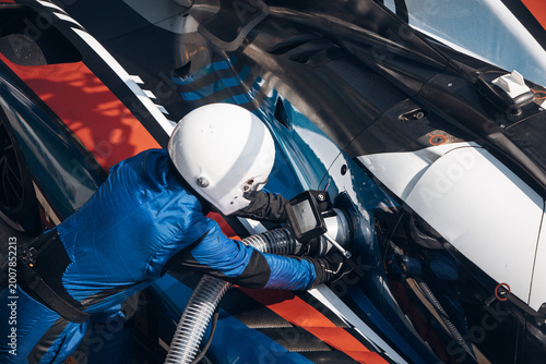Slika na platnu Team Mechanics refuel race car During a High-Speed Pit Stop in the Midst of an E
