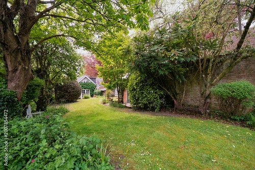 Picturesque view of a house in a vibrant green garden with lush trees and well-maintained grass during daylight hours.