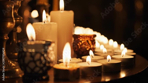 Warm candlelight from burning wax candles glows with a yellow flame on the church table, creating a romantic and peaceful atmosphere for the holiday celebration