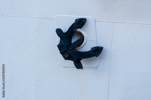 The black anchor of the  big ship was raised against the hull.