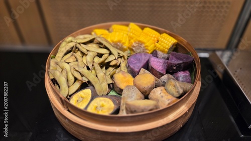 Assorted boiled vegetables including corn, sweet potato, banana, and beans served in a wooden bowl. Traditional Indonesian healthy side dish