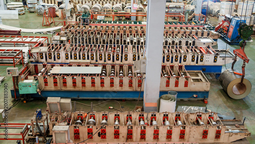 Photography Large Industrial Roll Forming Machine Producing Steel Roof Rolls in Gray Concrete Factory Setting ? Steel Sheet Manufacturing Process
