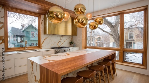 Modern kitchen with marble island, golden accents, and winter view.
