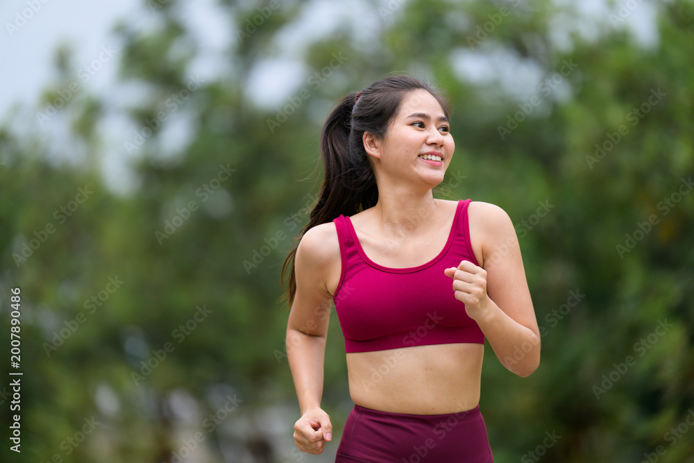 Fototapeta premium Young Asian woman running outdoors for fitness training