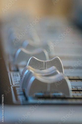 Close-up of audio mixer sliders with shallow depth of field and soft light creating abstract sound engineering background