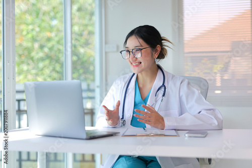 Female doctor working on laptop, providing remote healthcare services and virtual consultations in her office