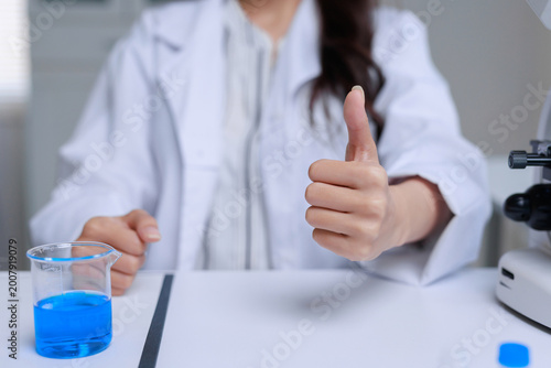Scientist in lab coat giving thumbs up, showing success and achievement in scientific research and discovery
