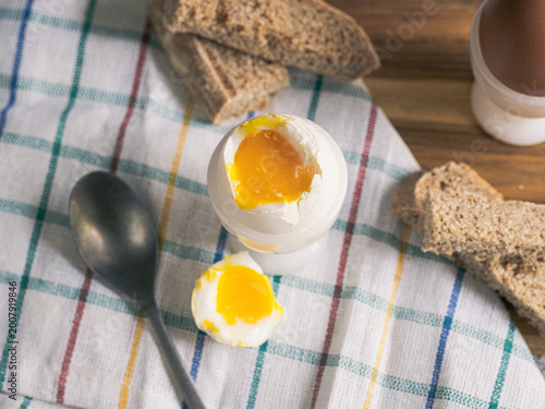 Konstfotografi Soft boiled egg in egg cup with runny yolk and bread, simple homemade breakfast