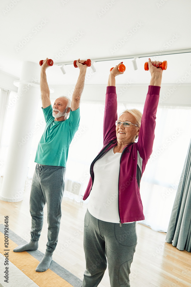 Fototapeta premium Senior couple exercise stretching and exercising with dumbbell lifting weigth at home health care