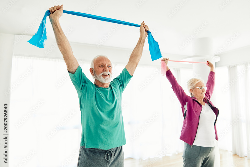 Fototapeta premium Senior couple exercise stretching and exercising with resistance band at home, health care and rehabalitation recovery concept