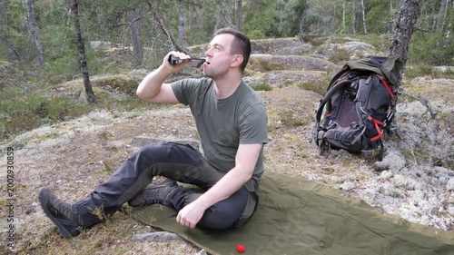 Male hiker resting with smartphone in forest campsite