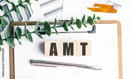 Amt concept with wooden blocks clipboard financial charts and pen on desk alternative minimum tax finance background