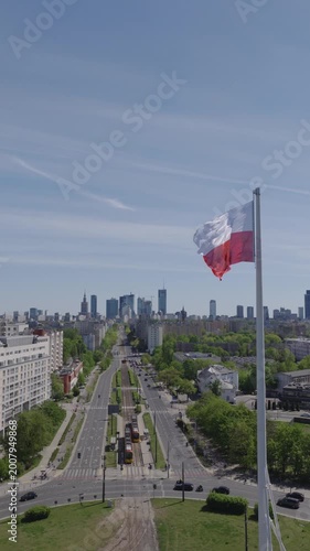 Warsaw skyline from drone with a large Polish flag waving above the city on a clear day