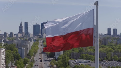 Warsaw skyline from drone with a large Polish flag waving above the city on a clear day
