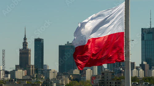 Warsaw skyline from drone with a large Polish flag waving above the city on a clear day